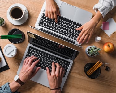 a man and woman working on laptops at a desk