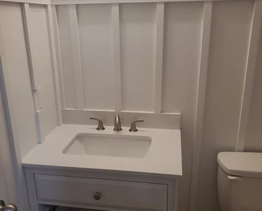 White bathroom vanity with board and batten wainscoting and silver faucet.
