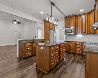 Modern kitchen with wood cabinets, granite countertops, a large island, and stainless steel appliances.