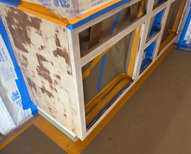 Sanded kitchen cabinets prepared for painting with 3M masking film and blue painter's tape.