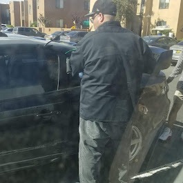 a man in a black jacket is standing next to a car