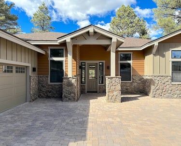 custom home with wood paneling, a driveway and large garage