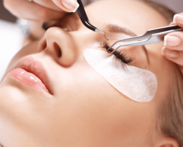 a woman getting her eyeliners done by a professional eyelashe