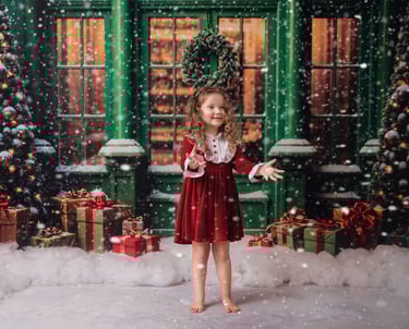 a little girl in a red dress standing in front of a christmas tree