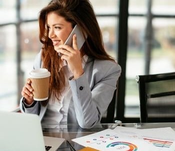 happy realtor working at desk and talking to client on phone