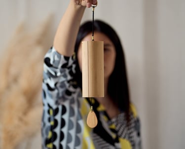 a woman holding a wooden wind chime