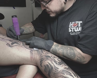 a man is getting a tattoo on his leg