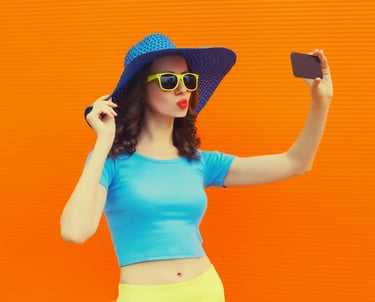 a woman in a blue top hat and sunglasses taking a selfie