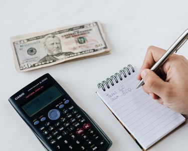 a calculator, US currency, and writing on a notepad