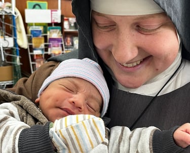 Franciscan Daughter of Mary holding a baby at the Rose Garden Home Mission
