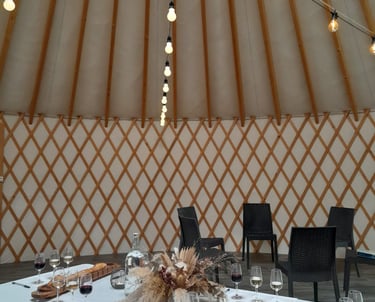 Wine tasting event setup inside a cozy yurt with string lights and charcuterie boards.