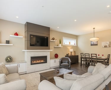 Modern open concept living room featuring a gas fireplace, wall-mounted TV, and adjacent dining area.