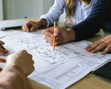 Hands of stakeholders refining a detailed diagram, illustrating adaptive and precise approaches