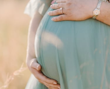 a pregnant woman in a blue dress with flowers on her belly