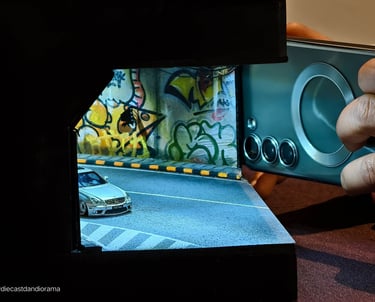 a person taking a picture of a 1/64 model car in a picture