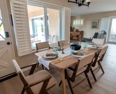Modern wooden dining table set with mid-century chairs in a bright, open-concept home interior.