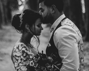 le marié qui embrasse la mariée sur le front dans une allée de platane