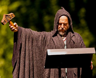 Oficiante vestido con túnica medieval marrón y capucha alzando una espada cerimonial durante una bod