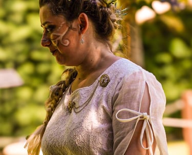 Retrato de la novia con vestido medieval y trenza adornada con flores, mirando hacia abajo