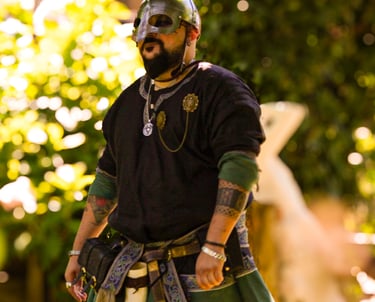 Hombre en ceremonia de boda medieval con chaleco y espada ornamental en un entorno forestal