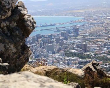 a boulder in the foreground, with a cityscape in the distance, far below the photographer's height