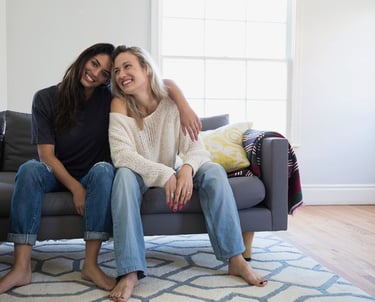 two women sitting on a couch in a living room martin pe coach de parejas