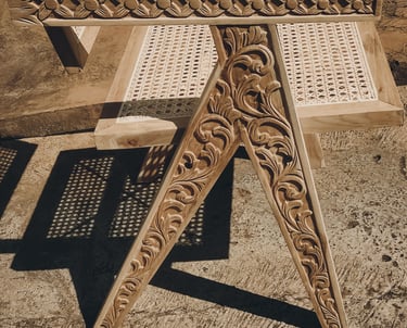 A teak wood chair featuring a combination of hand-carved wooden elements and woven rattan details.