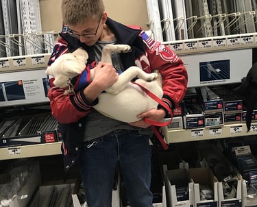 a student puppy raiser cradles his puppy in his arms looking down lovingly at her