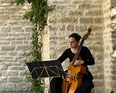 Claire playing a cello in a courtyard