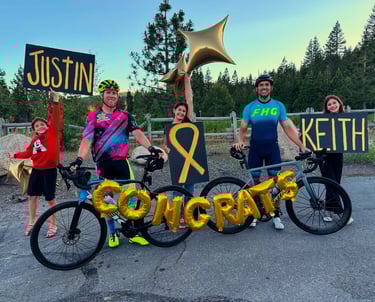 A group of people with balloons and a congrats sign with two cyclists