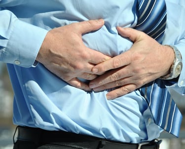 Man clutching abdomen due to cramp or bloating