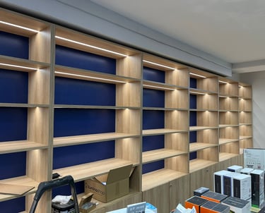 Custom wood shelving unit with integrated LED strip lighting and navy blue back paneling.