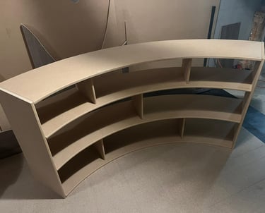 Custom curved wooden bookshelf made of MDF being assembled in a woodworking workshop.