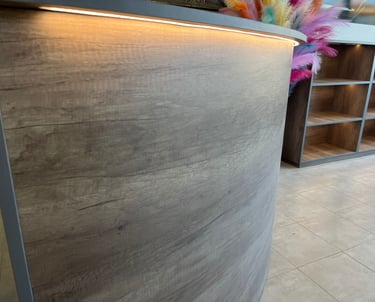 Curved wood reception desk with LED strip lighting in a modern commercial office interior.