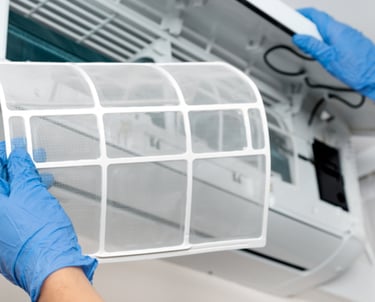 Una persona con guantes sosteniendo un filtro de aire acondicionado