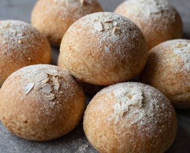 Freshly baked golden bread loaves arranged on a rustic wooden table with a linen cloth.