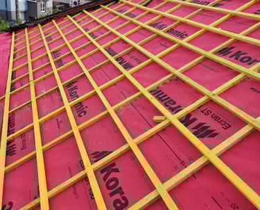 Installation de liteaux et d’un écran de sous-toiture rouge pour préparer la pose des tuiles, sur un chantier de rénovation à