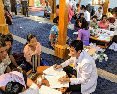 Dr Zaw wearing a smile seeing patients and family members sitting in front of him