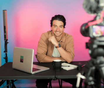 a man sitting at a table with a laptop and a camera