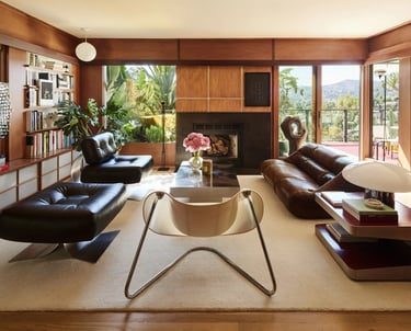 Modern living room with leather furniture and large windows.