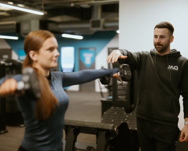 Client doing lateral dumbbell raise in Leamington Spa gym, coached by trainer focused on form and shoulder activation