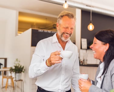 Two office colleagues drinking coffee and laughing