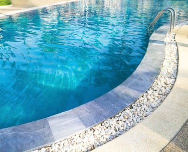 Curved backyard pool with clean blue water and pebble-lined edge, maintained by Piscus Pools in Los Angeles.