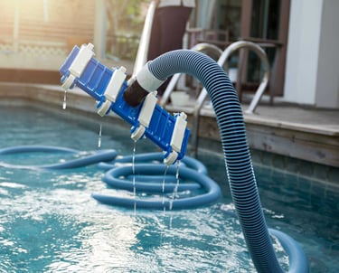 Close-up of pool vacuum equipment being used during a professional pool cleaning visit.