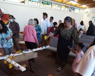 Filipino, Samoan and white people laying flowers on a cross