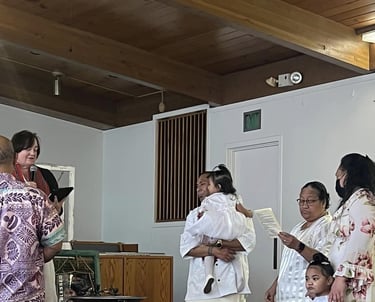 two Samoan children being baptized with parents and adults.