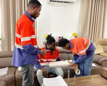 Three professional movers in orange high-visibility shirts with reflective stripes collaborate to wr