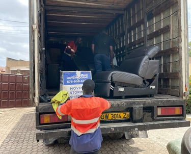 A professional mover in an orange high-visibility vest with reflective strips and blue pants, holdin