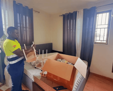 A professional mover in a yellow high-visibility vest with reflective strips and Ghanaian flag patch