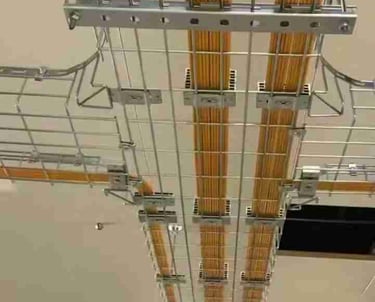 a metal wire mesh cable tray hanging in the ceiling with yellow cables